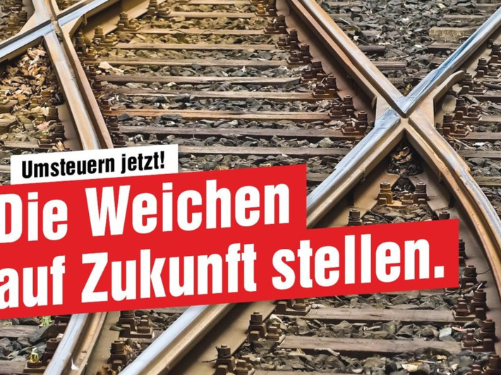 Das Foto zeigt in der Nahaufnahme sich kreuzende Bahngleise, dazu die Aufschrift "Die Weichen auf Zukunft stellen.".